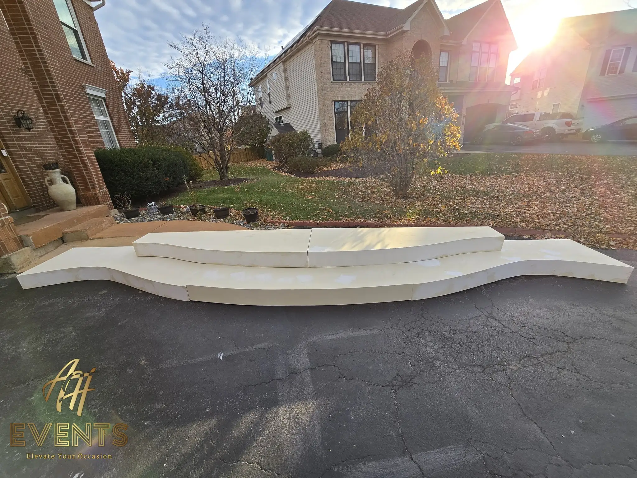 Cream serpentine stage riser sections laid out on a driveway at golden hour during fabrication