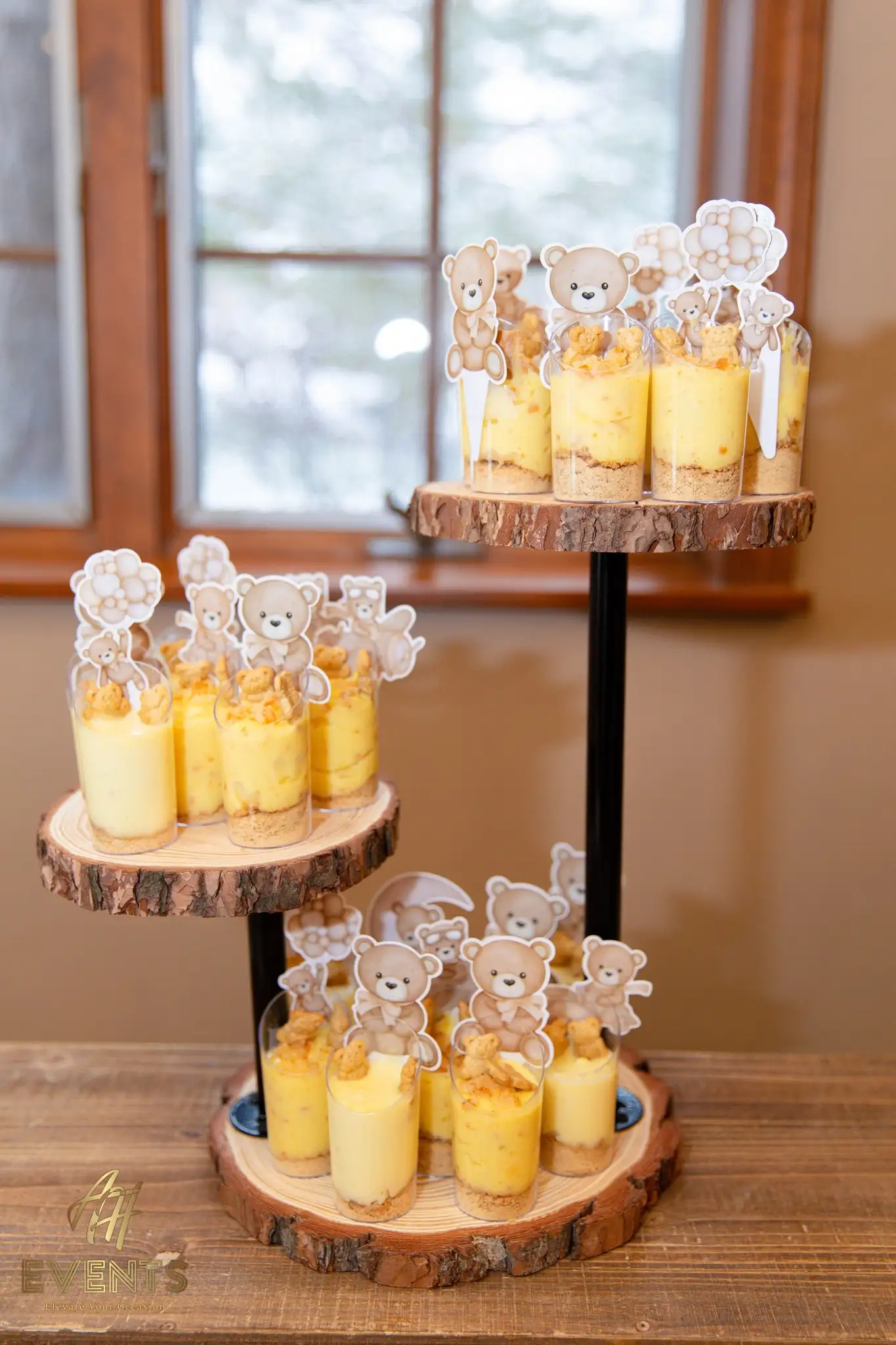 Tiered wood-slice stand of pudding dessert cups topped with teddy-bear picks