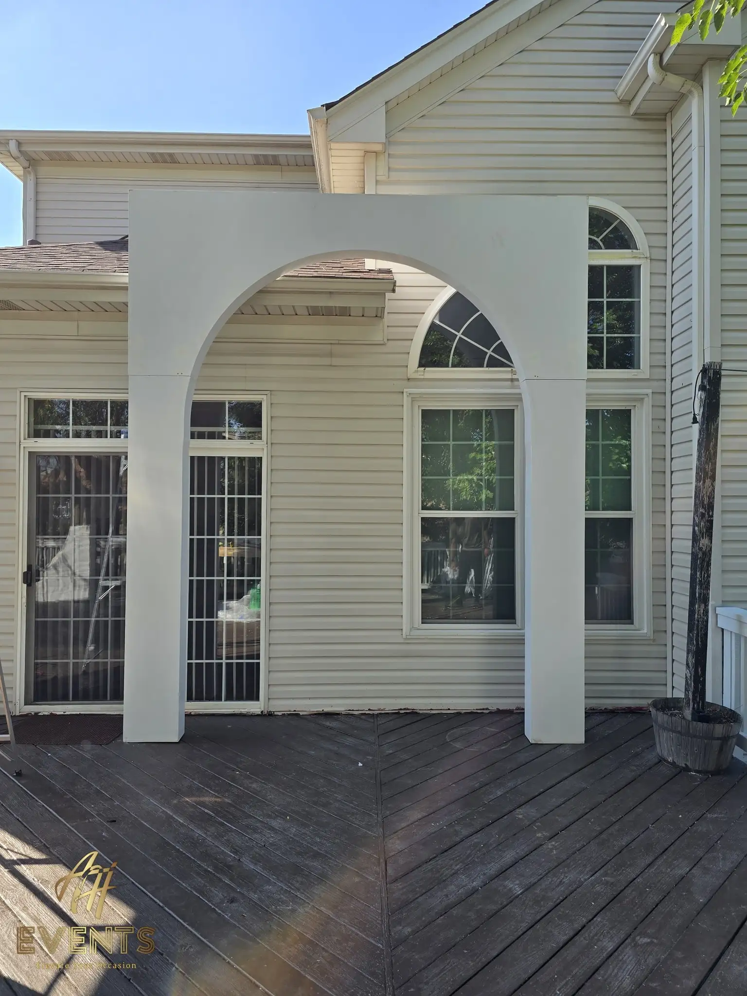 White square arch with a rounded interior opening on a deck beside a potted plant