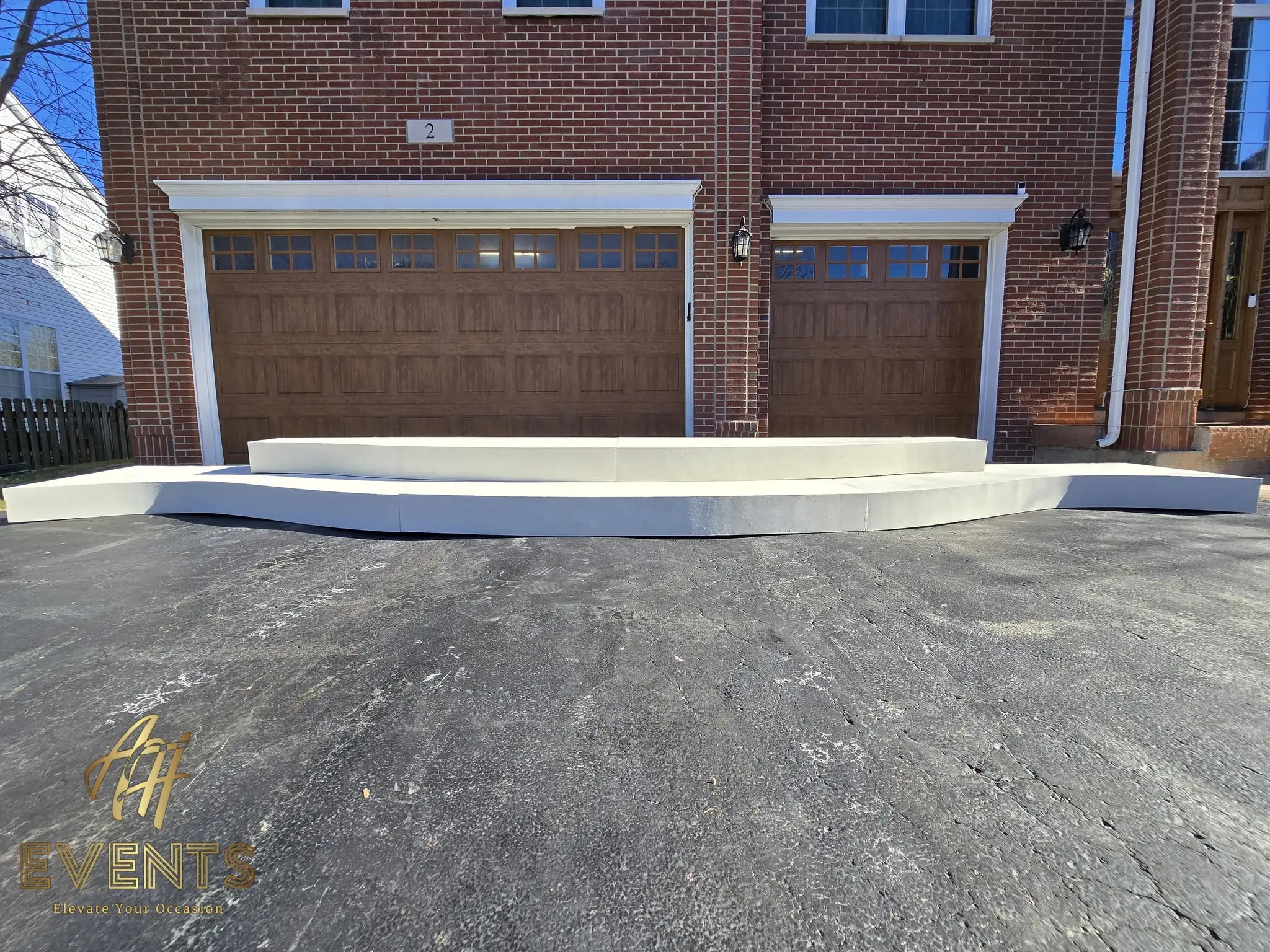 Long white contoured stage riser installed across a driveway in front of the garage