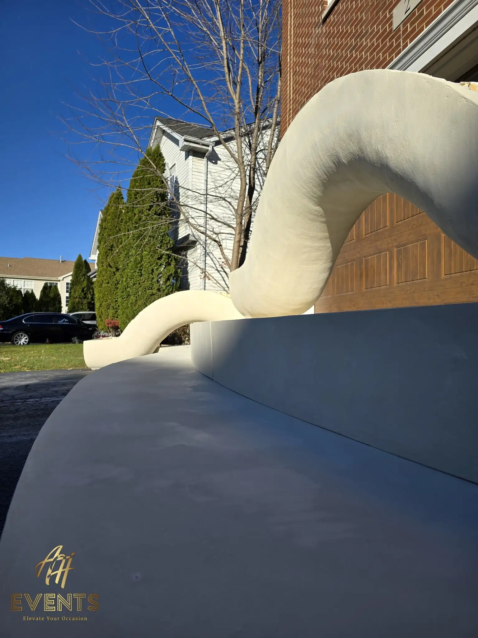 Low-angle view of the sculpted white-and-gray serpentine stage forms beside a driveway