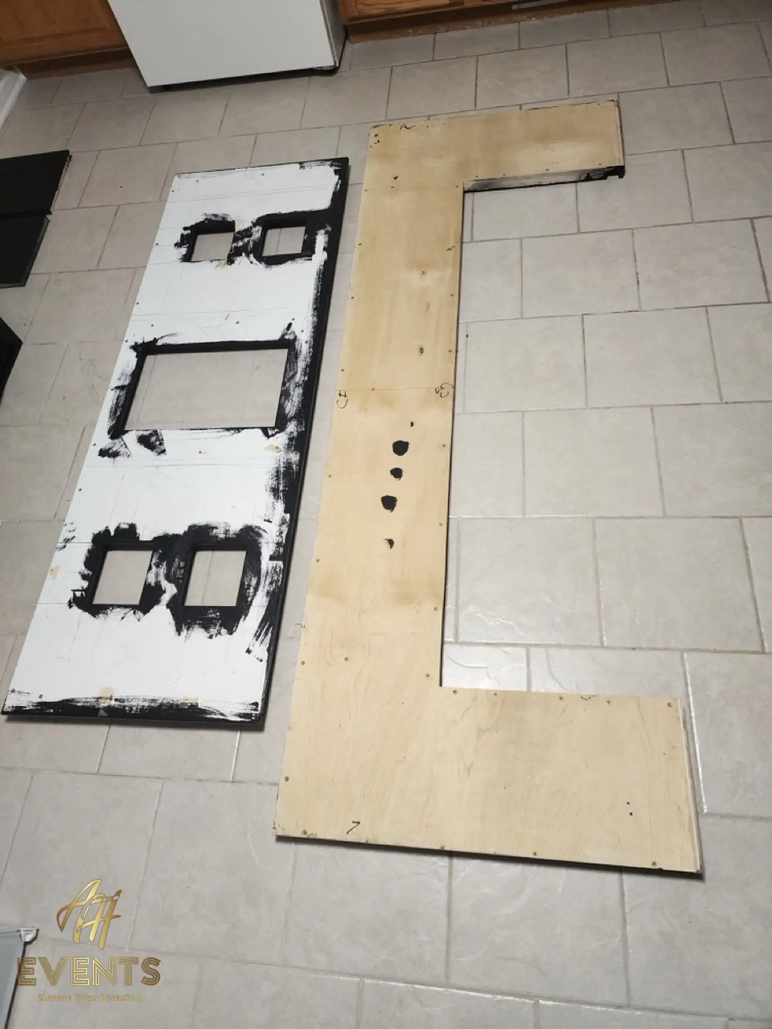 Bobawala cart panels during fabrication on a tile floor — a cut black front panel and an L-shaped plywood counter piece