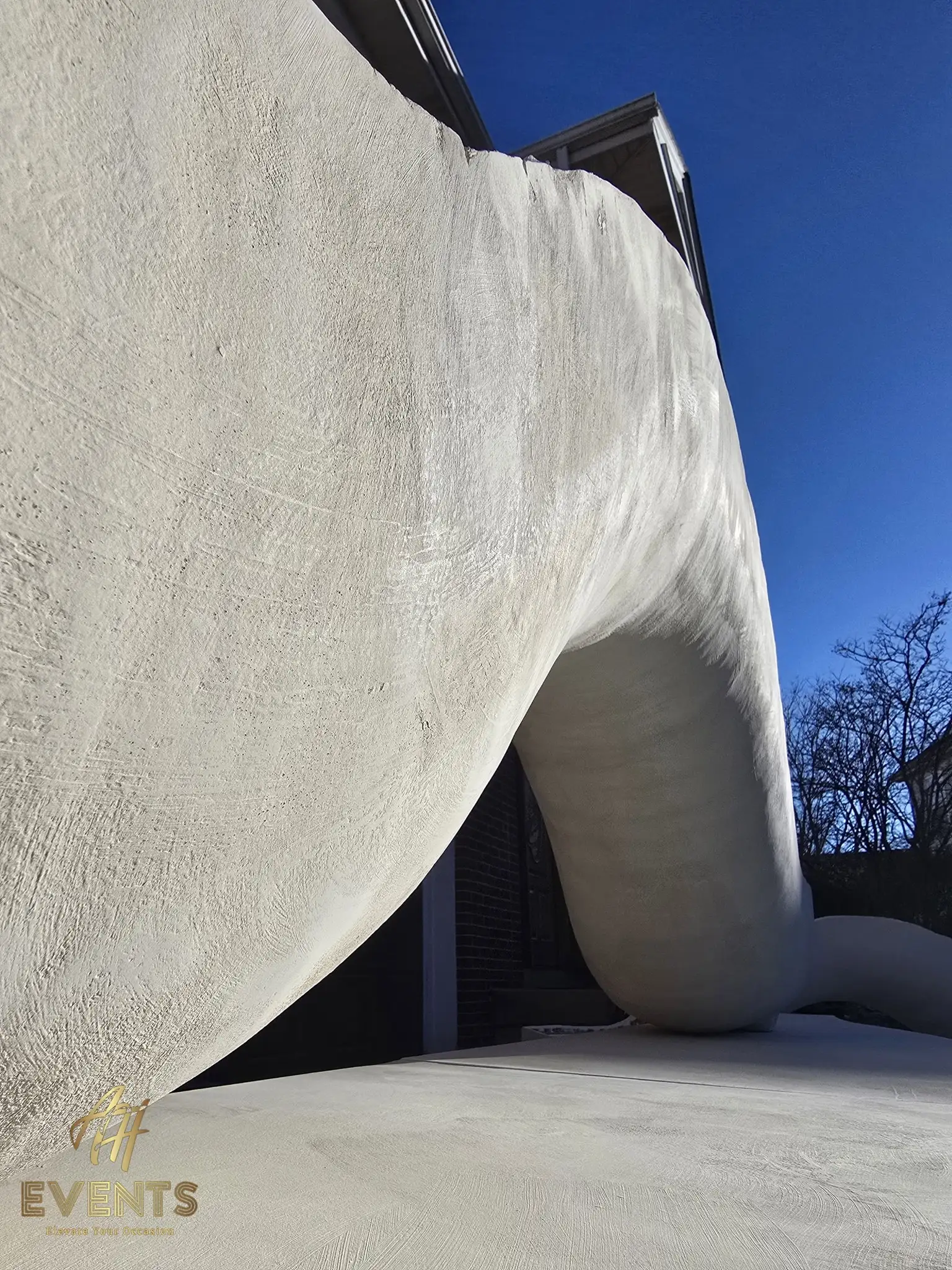 Sculpted white serpentine form sweeping down to the platform against a clear blue sky
