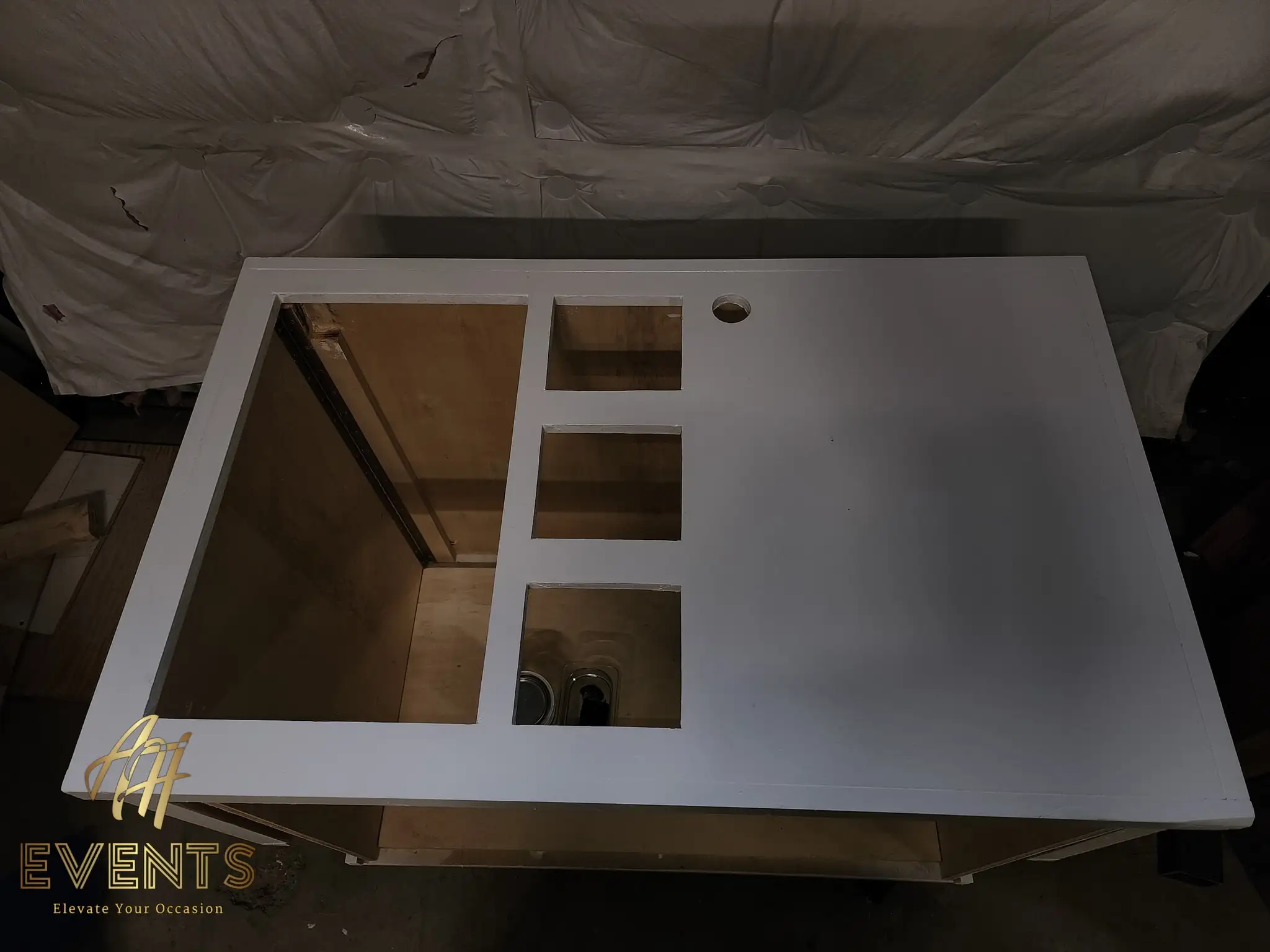 Gray-primed cart top in the spray booth with a column of square wells, a large open well and a round hole