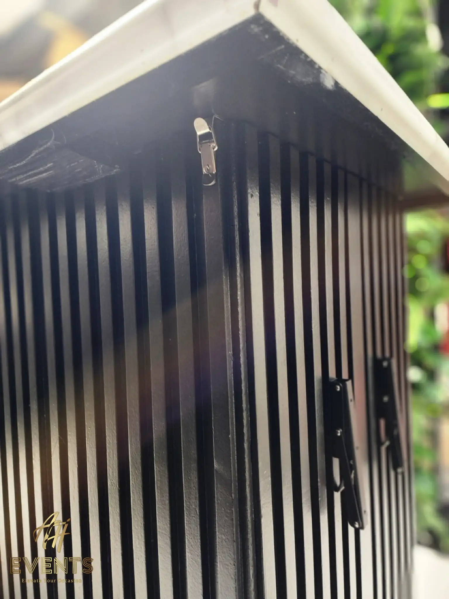 Corner detail of the Bobawala cart showing a silver latch and black folding brackets on the slatted panel