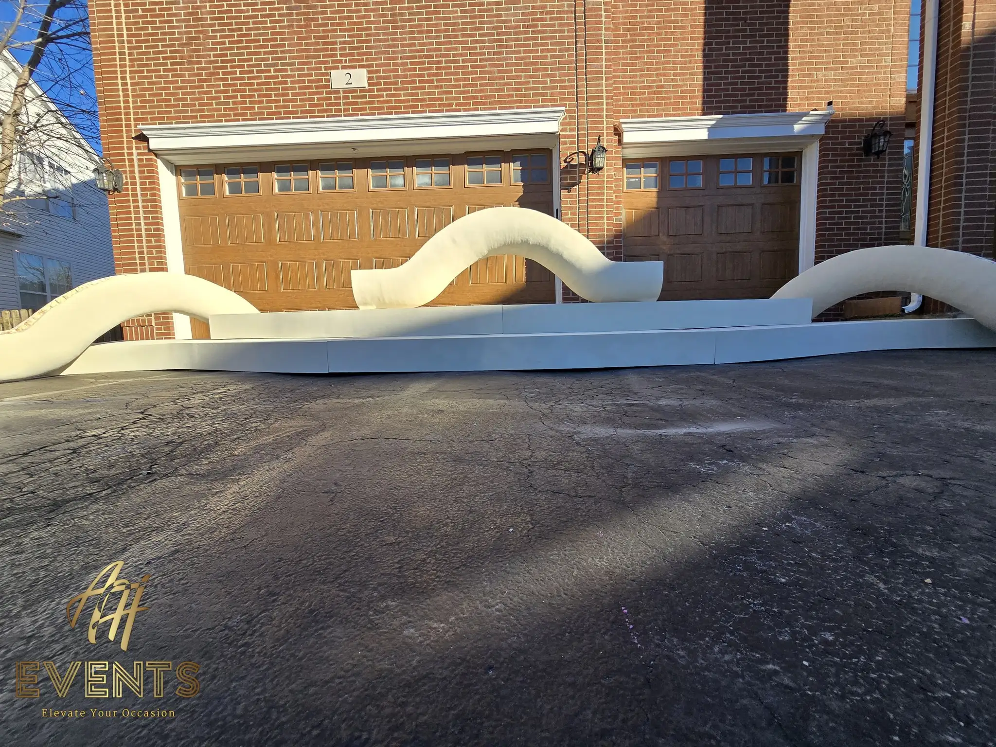 Wide view of the white serpentine contoured stage backdrop in front of the garage