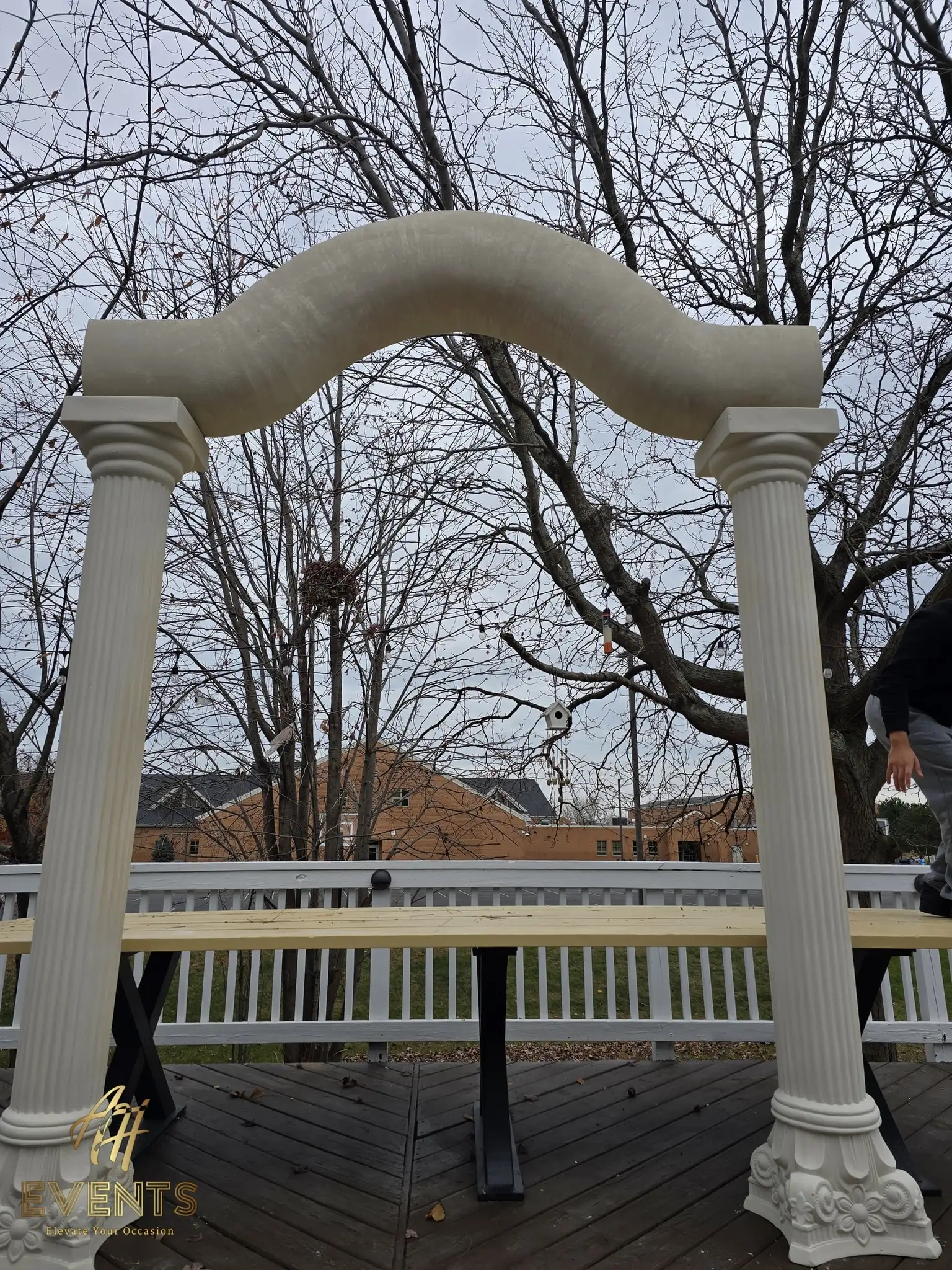 Fluted columns supporting the serpentine arch on the deck, bare trees behind