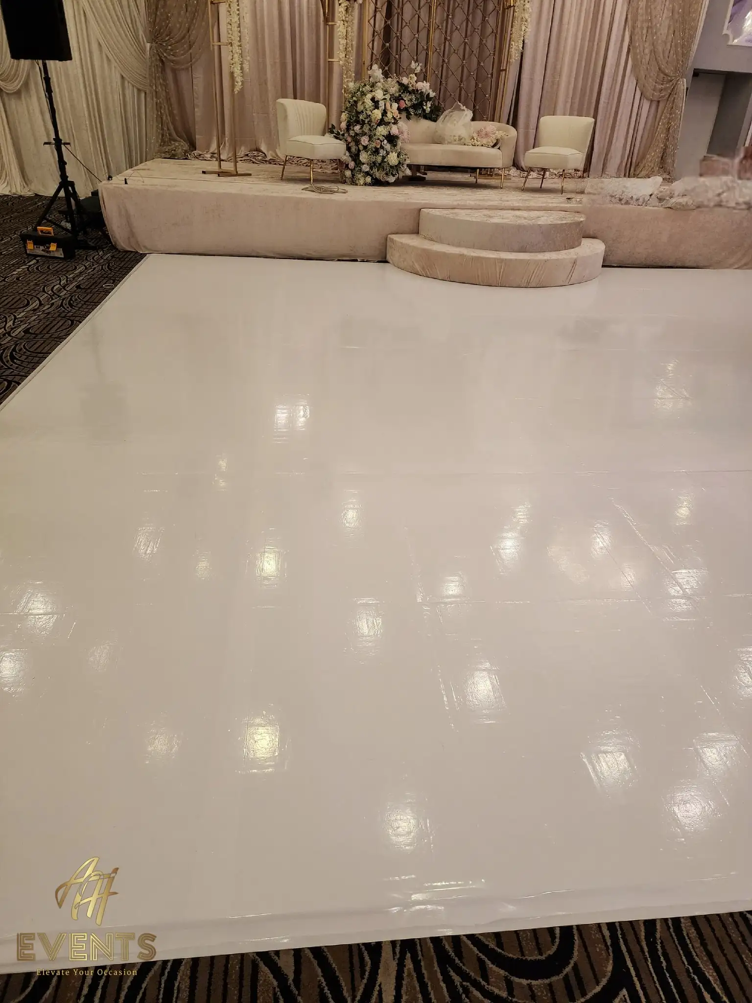 Close view of the glossy white dance floor reflecting lights, the blush stage behind