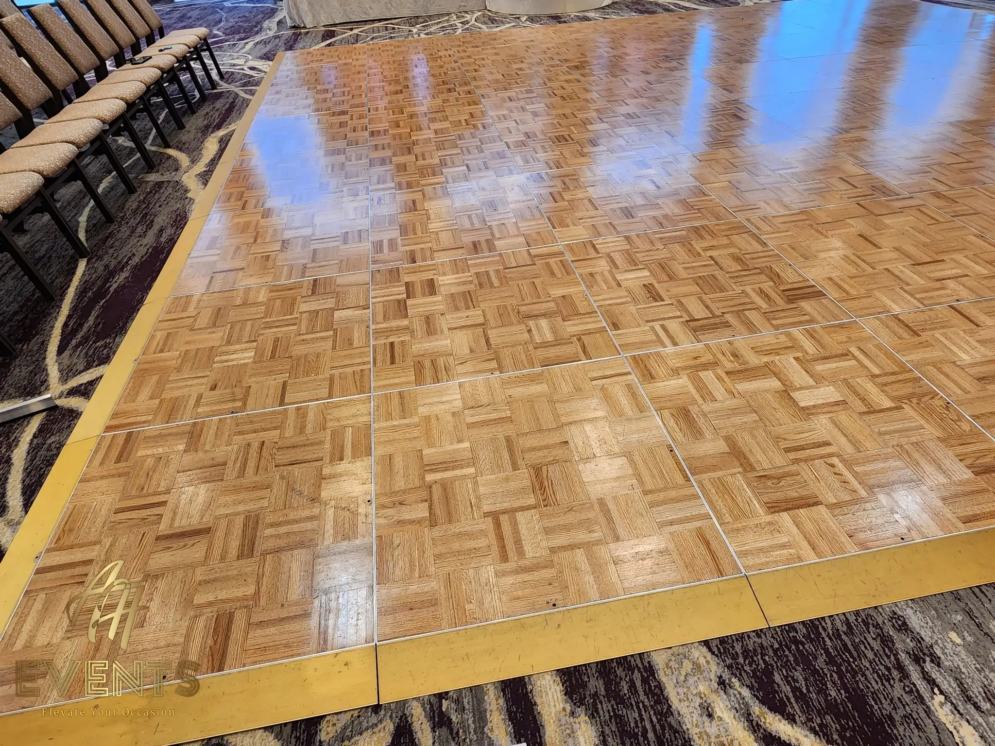 Polished parquet wood dance floor with a gold-trim border, gold chairs to the side