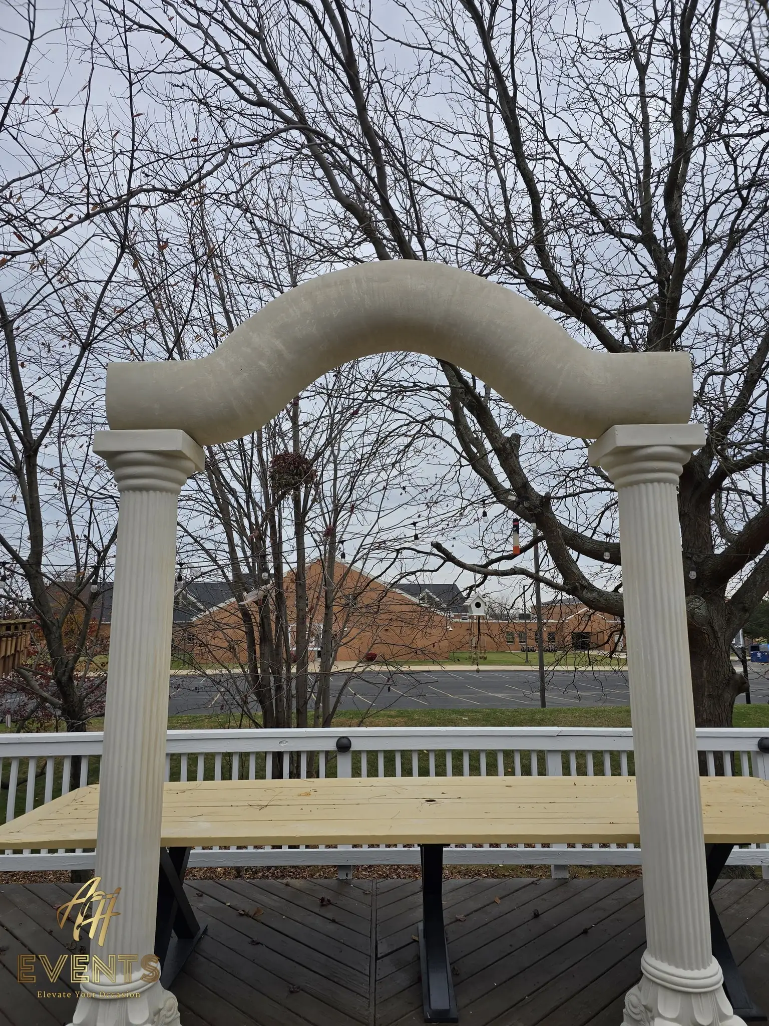 The serpentine arch and columns assembled over the plywood platform, trees behind