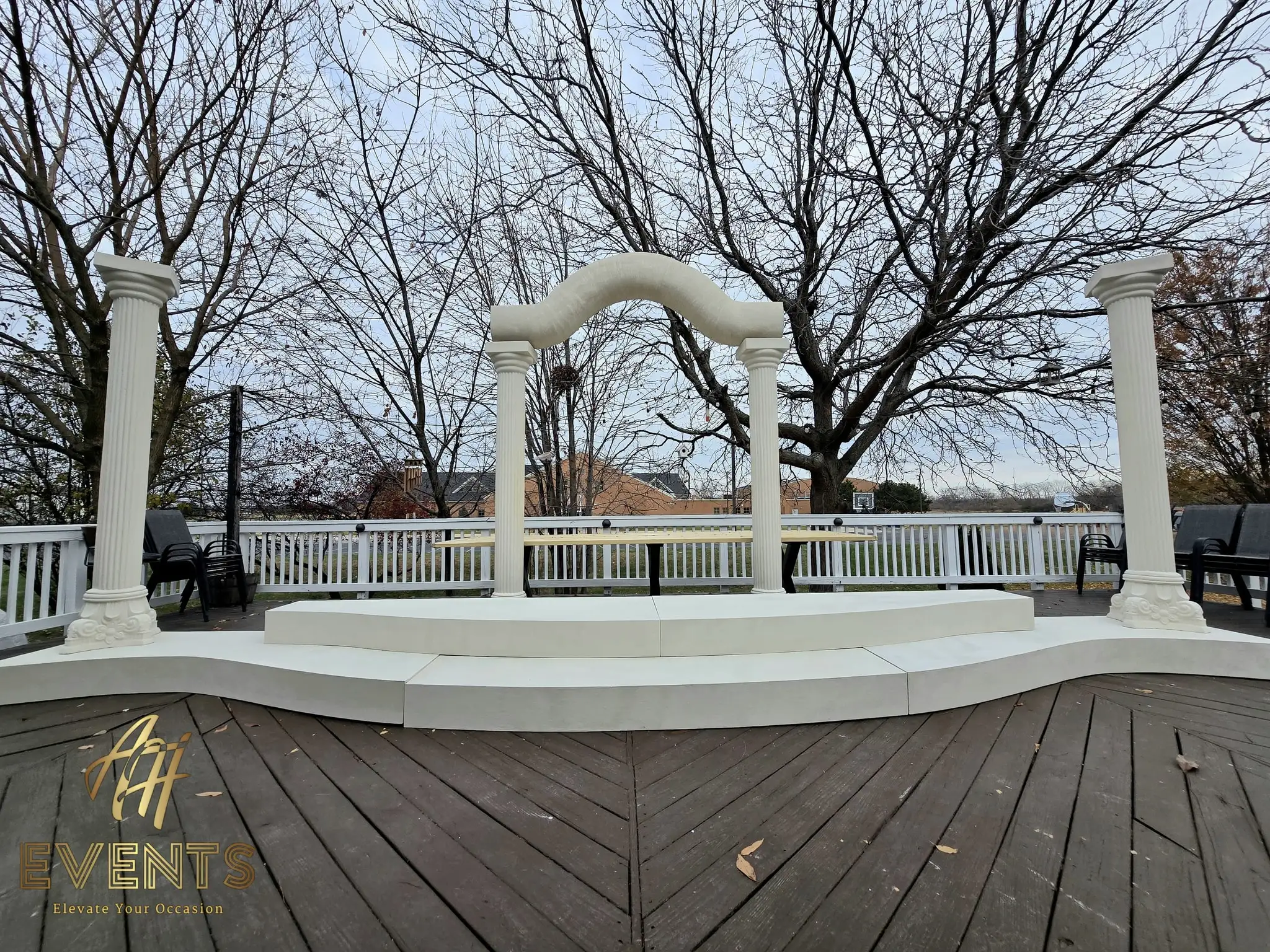 Finished classical-pillar stage with a curved white riser, fluted columns and serpentine arch on the deck