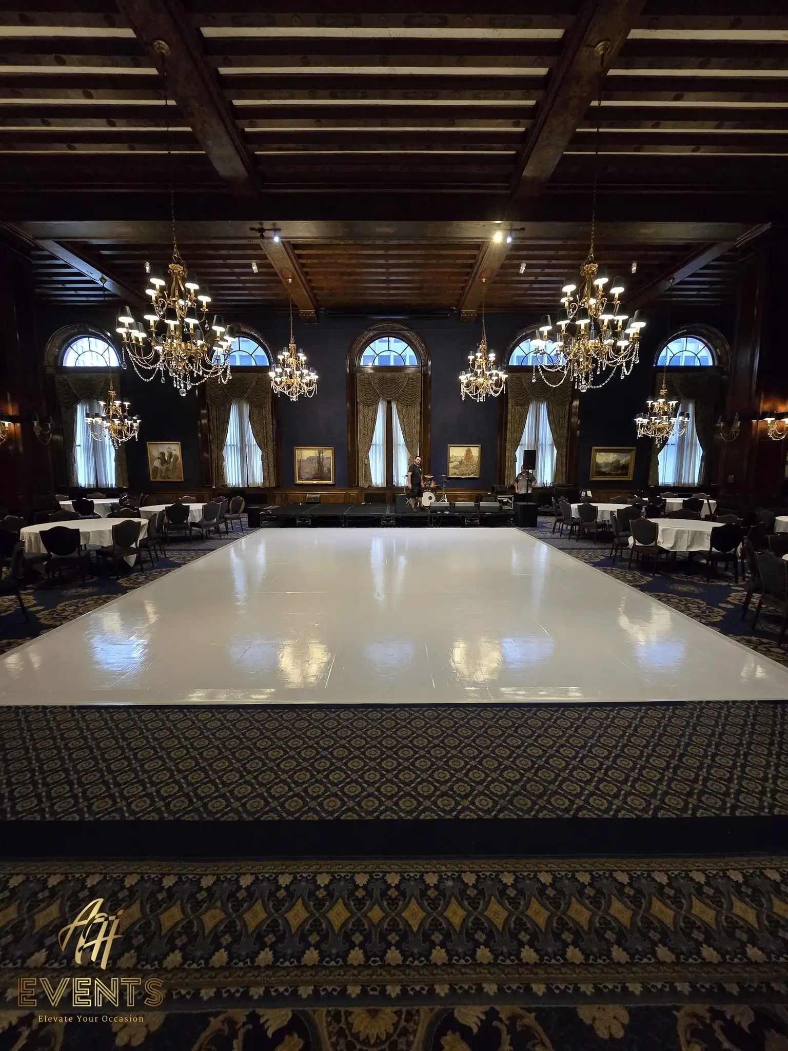 Glossy white dance floor in the historic navy wood-beamed ballroom with chandeliers and a patterned carpet